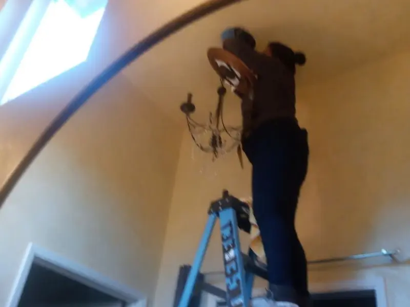 Electrician installing a chandelier in a Erie residence